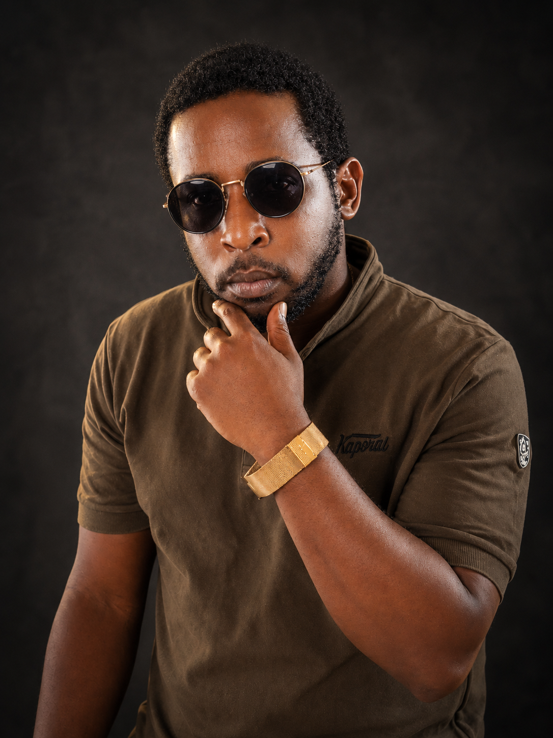 OCHOMANE portant des lunettes rondes sur un fond sombre