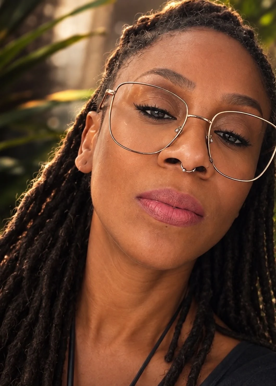 Portrait rapproché de Jahina Noël avec des lunettes et des cheveux tressés.